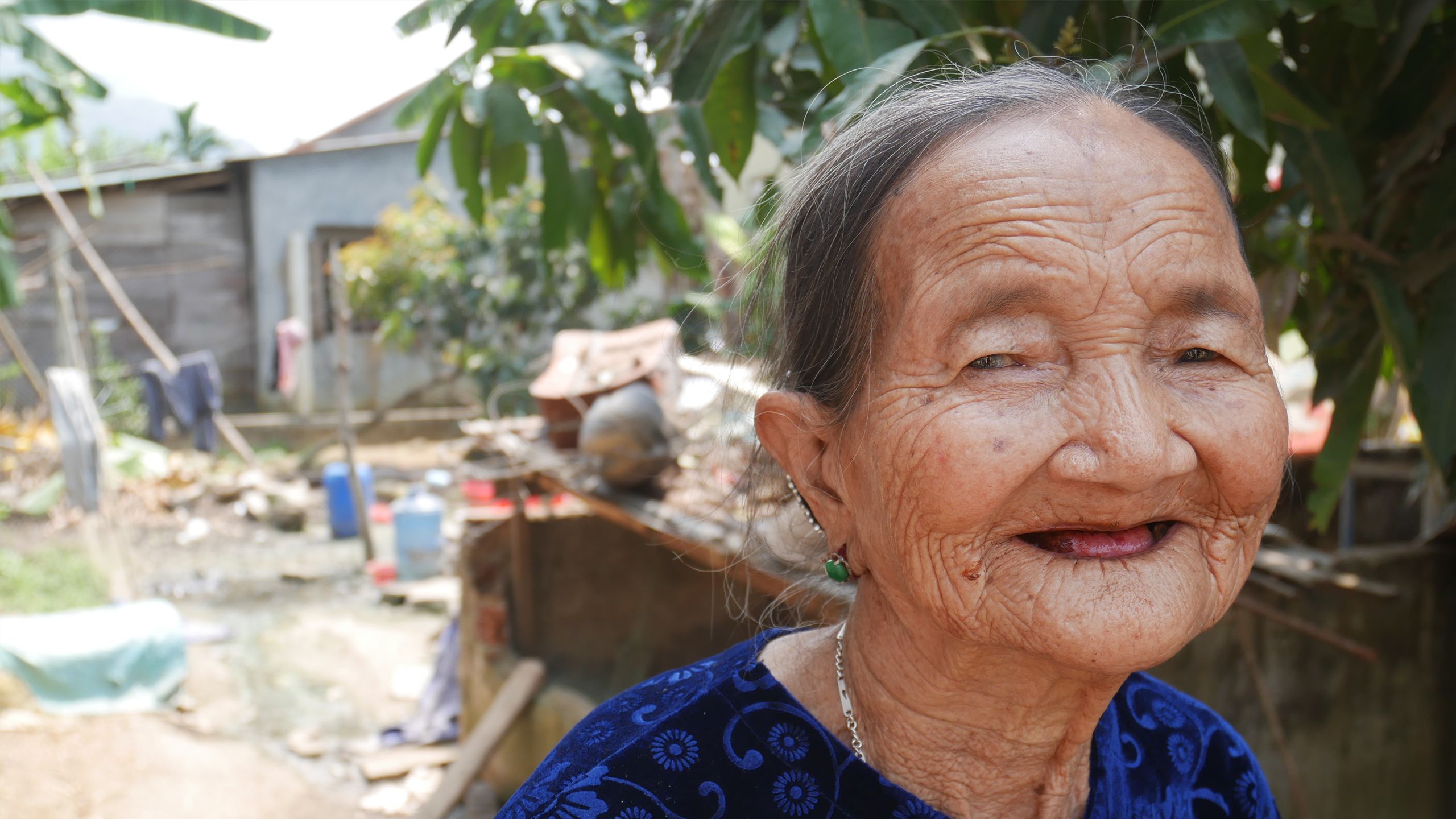 An elderly Vietnamese woman is seen standing in front of her damaged home after it was hit by typhoon Damrey.