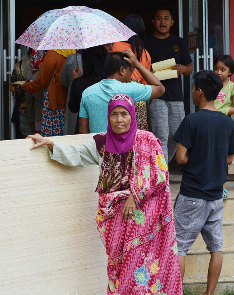 An Elderly woman receives shelter assistance consisting of plywood, nails and lumbers.